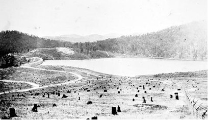 Photograph taken circa 1927 showing the reservoir, dam wall, roads, fencing and eastern hillside prior to planting and after the 1926 bush fire