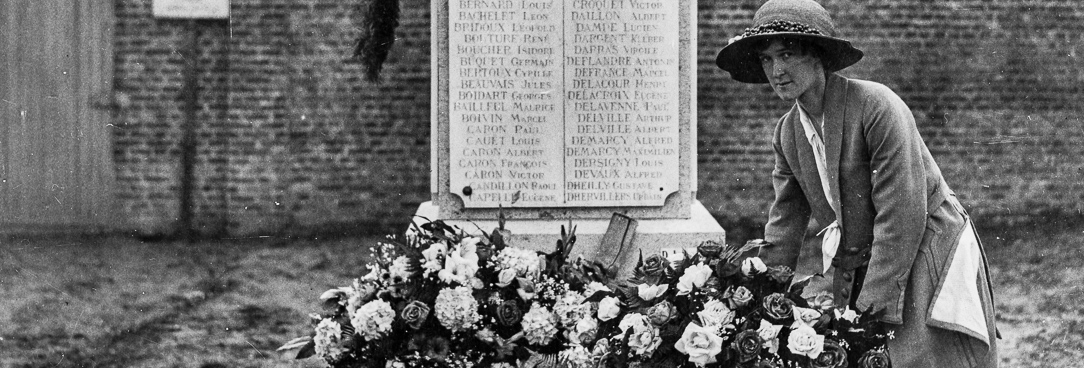 Black and white photo, woman lays flowers at a memorial