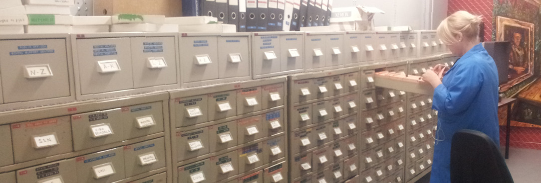 clour image of female PROV staff member looking through card catalogues in repository