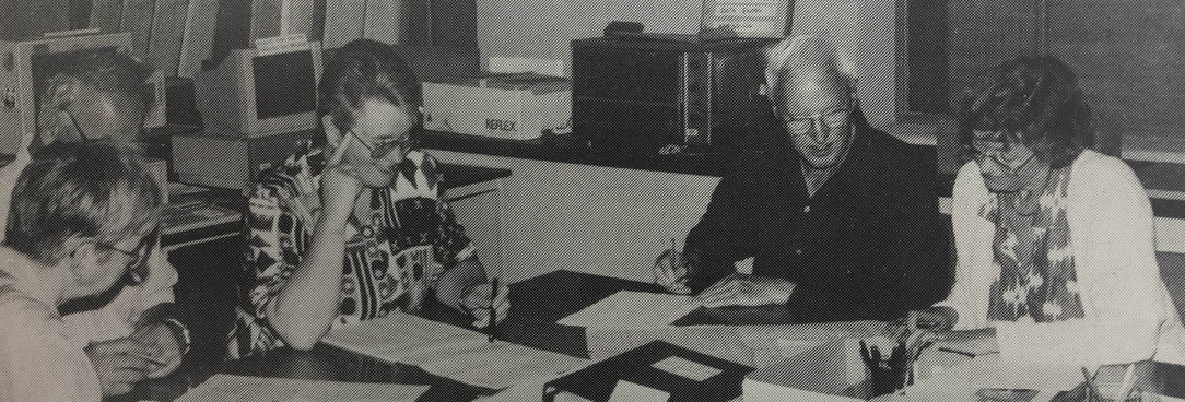 black and white photo of volunteers looking over documents