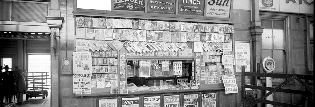 Spencer Street main concourse newspaper kiosk with painted signs for The Age, The Sun, The Weekly Times and The Herald. 18TH July 1936. VPRS 12800/ P3  item ADV 1151