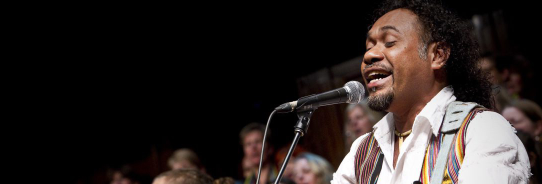 Man singing and playing guitar to an audience