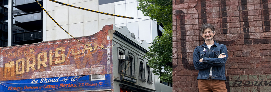 Sean Reynolds leaning against a wall with a ghost sign 