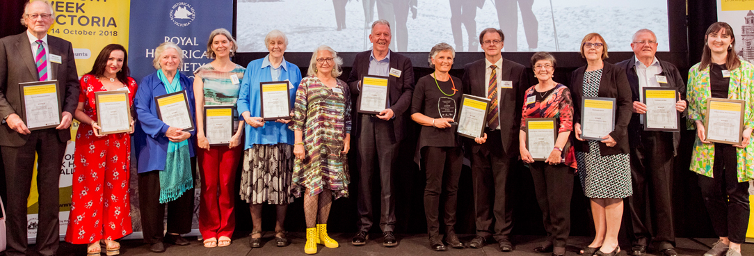 photo of winners standing on stage holding up their certificates