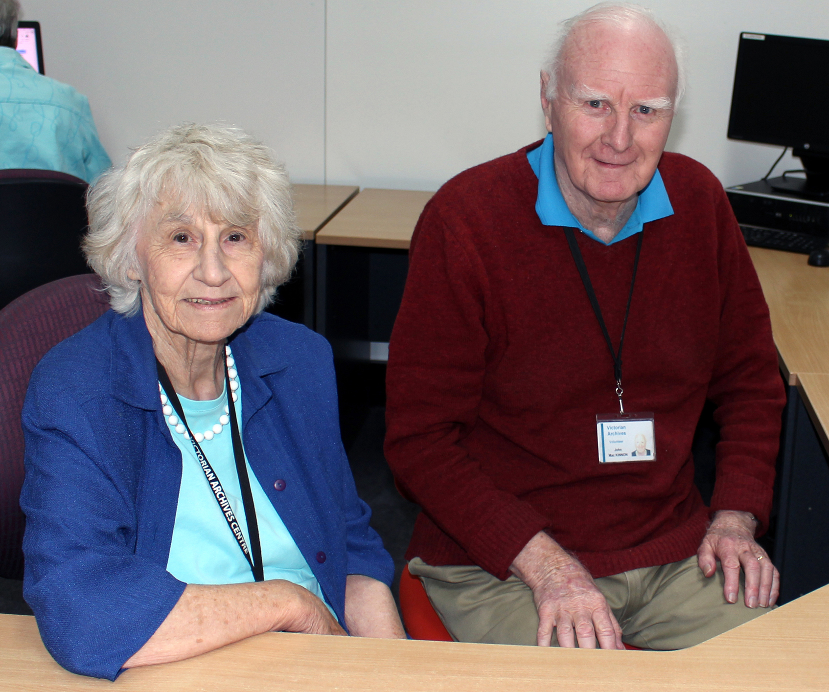 colour photo of Millie and John sitting at a desk