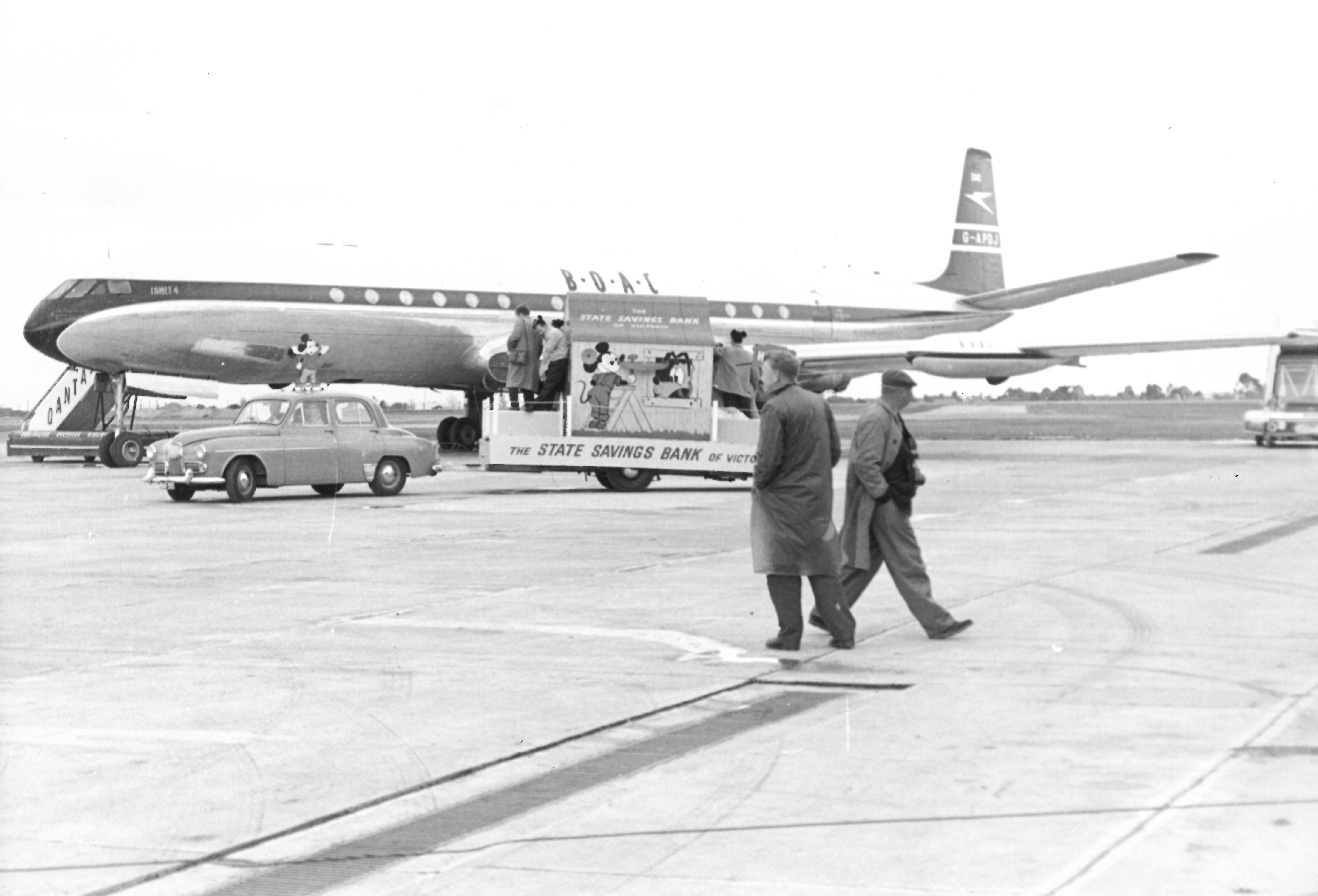 black and white photo of a plane with the mickey mouse float waiting beside it