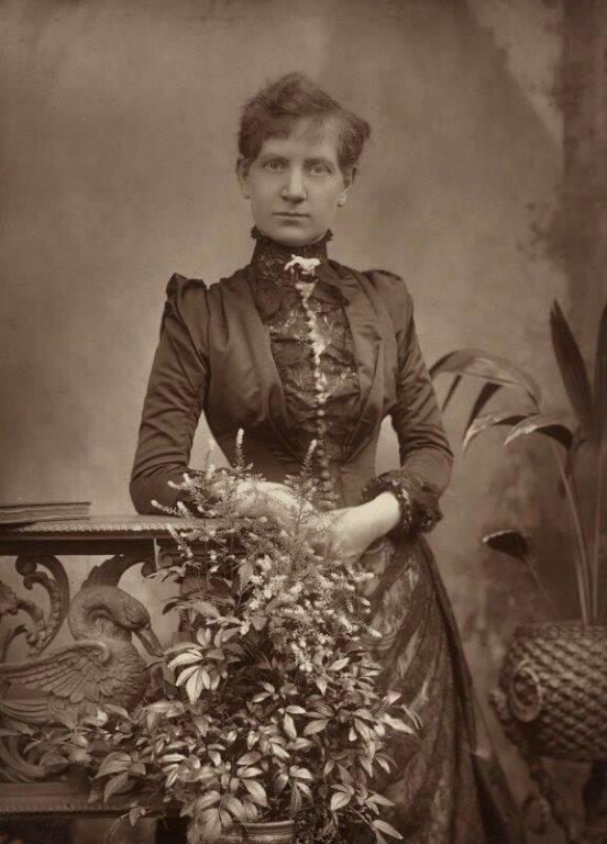 Black and white photograph of a woman posing in a studio in 1889