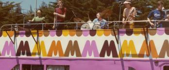 colourful photo of a band playing on top of a Big M branded pink bus