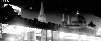 photo of melbourne at night from the view point of a train station platform, the dome of flinders street station can be seen in the distance