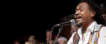 Ego Lemos and the 2012 Millennium Chorus. Photo by Jorge de Araugo. Courtesy of The Boîte. Man singing and playing guitar to an audience