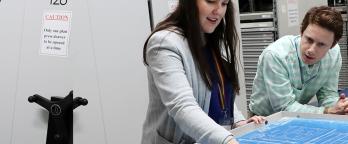 two people in an archive repository looking at a plan