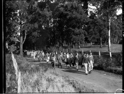 black and white photo of people walking through a park