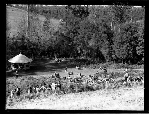 black and white photo of people walking through a park