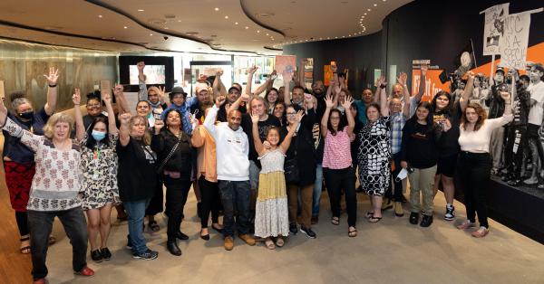 a group of people with their arms in the air in the exhibition space