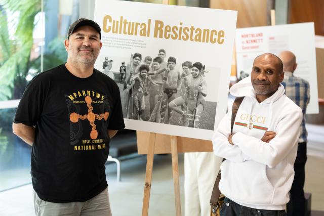 two people standing in front of a placard