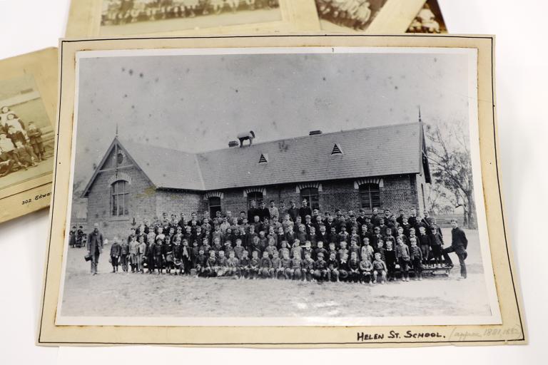 A photograph of a mounted black and white photograph of a 19th century school and children